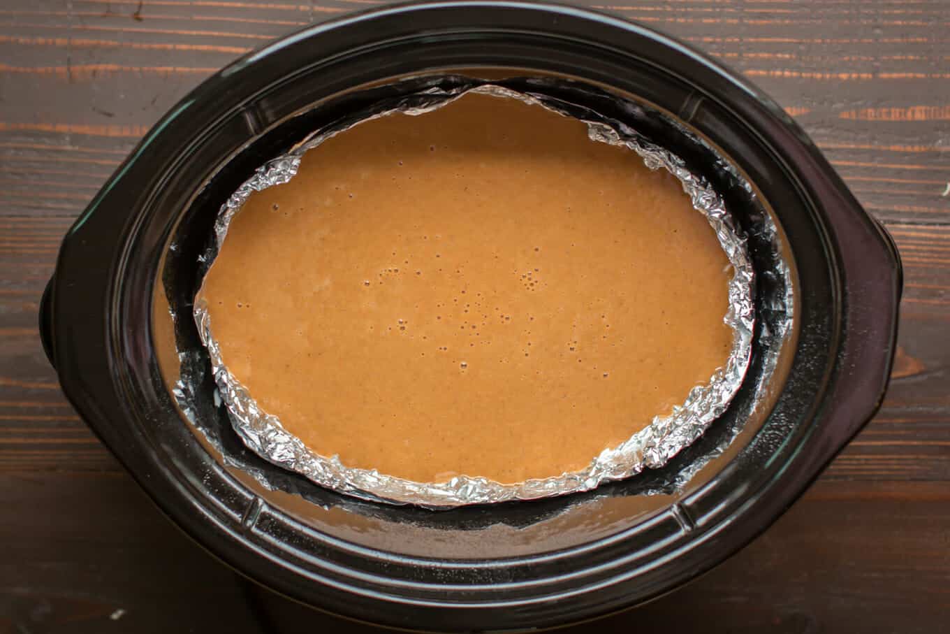 uncooked pumpkin pie filling in the slow cooker (lined with foil).