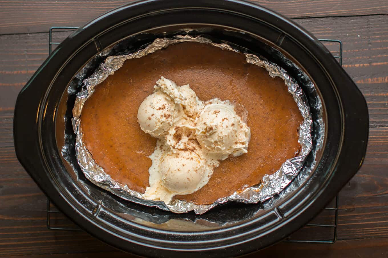 cooked pumpkin pie in the slow cooker with 3 scoops of ice cream on top.