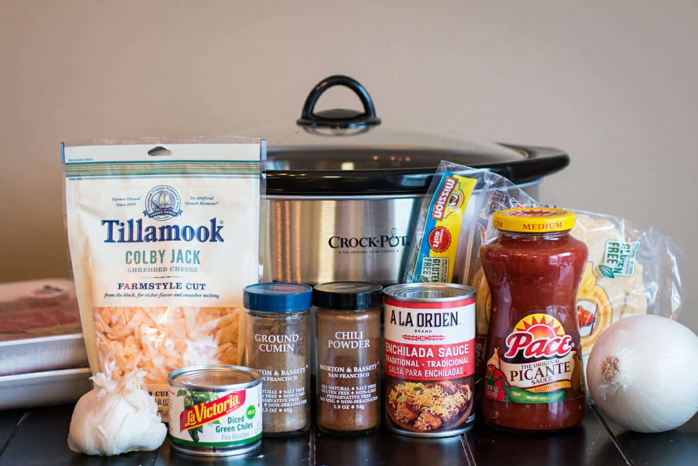 salsa, tortillas, beef, cheese, green chiles, seasonings in front of slow cooker.