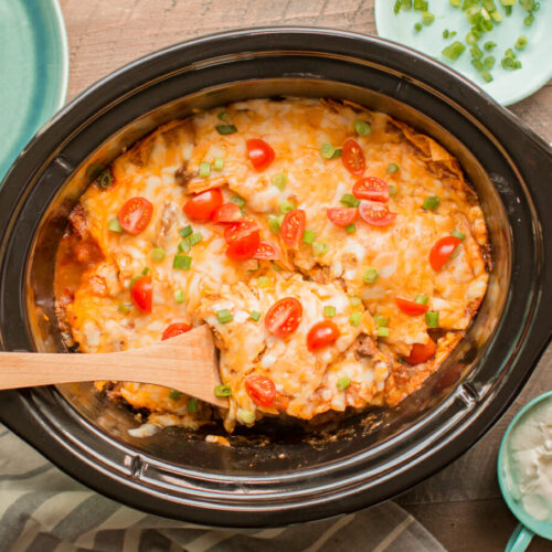 beef enchilada casserole with wooden spoon in it.