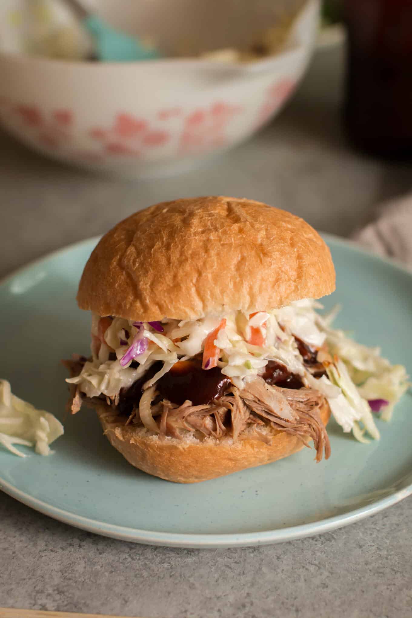 pulled pork on bun with coleslaw and barbecue sauce