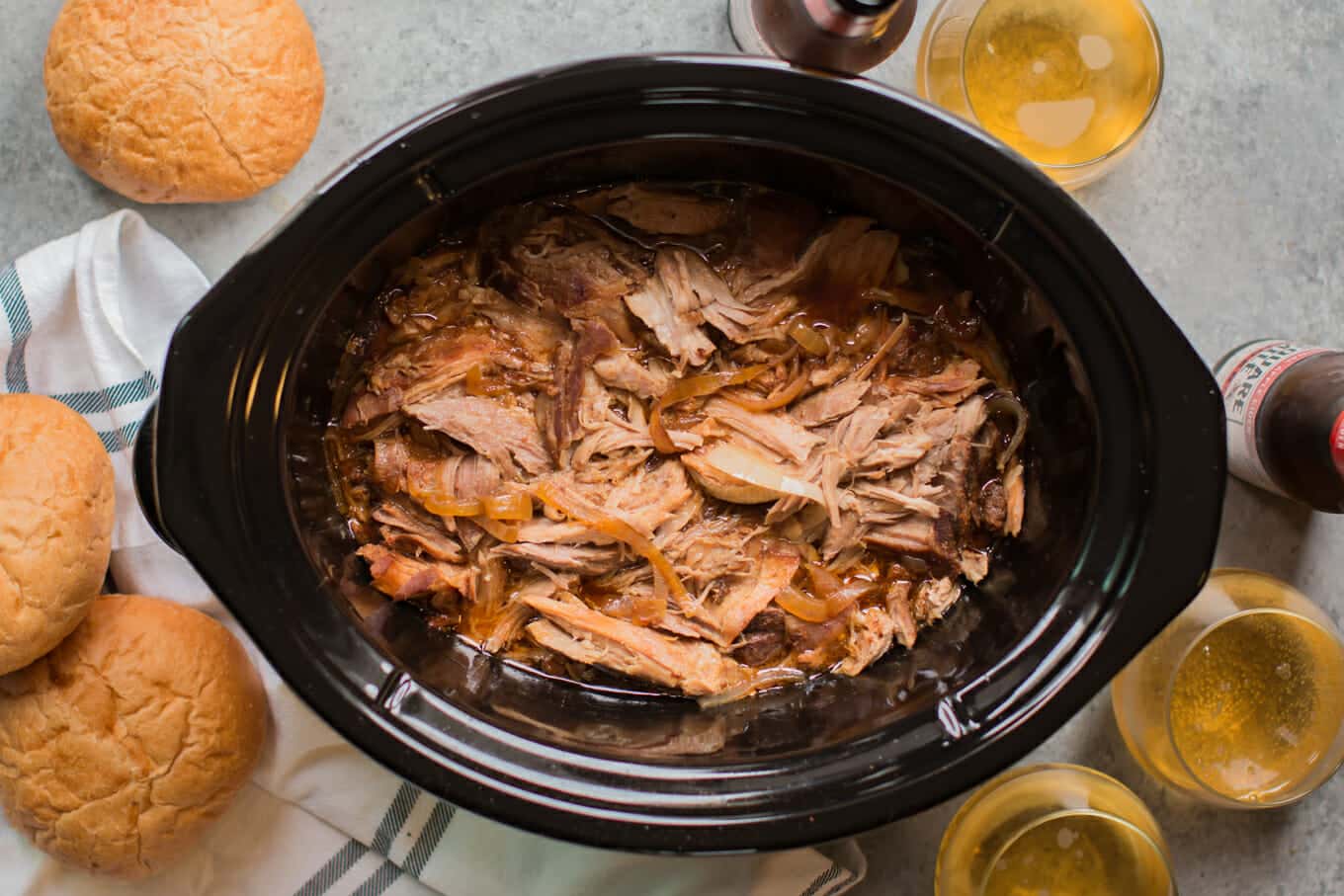 shredded pork in slow cooker with buns on the side.