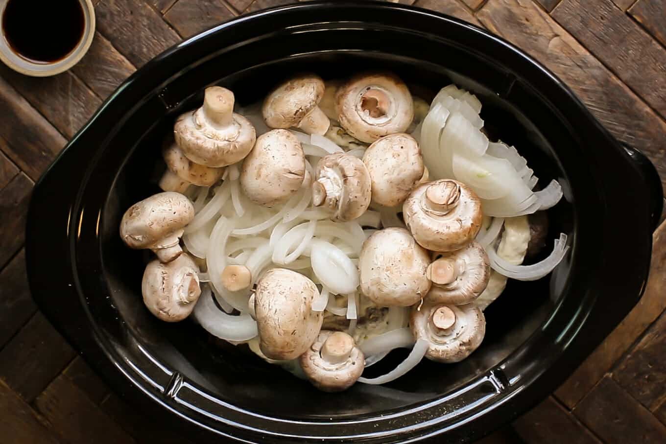 raw onions and mushrooms on top of a roast.