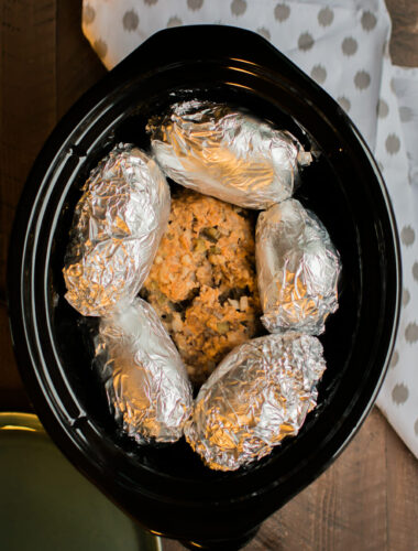 cooked meatloaf with foil wrapped russet potatoes on top.