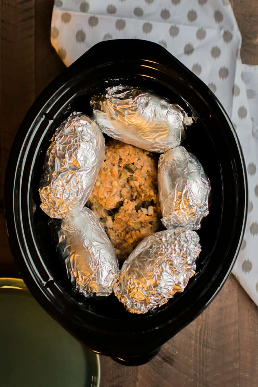 cooked meatloaf with foil wrapped russet potatoes on top.