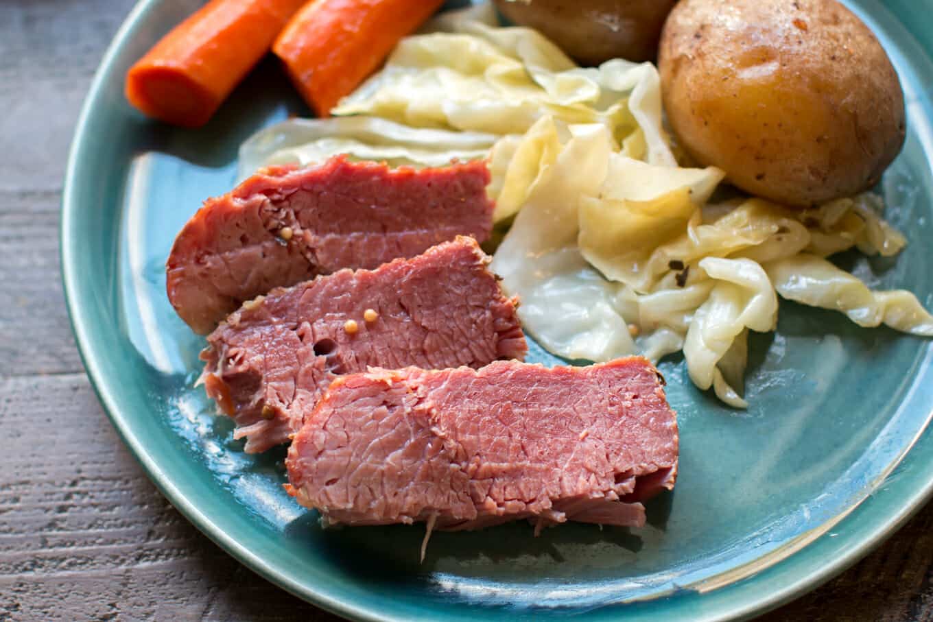 sliced cooked corned beef on a teal plate.