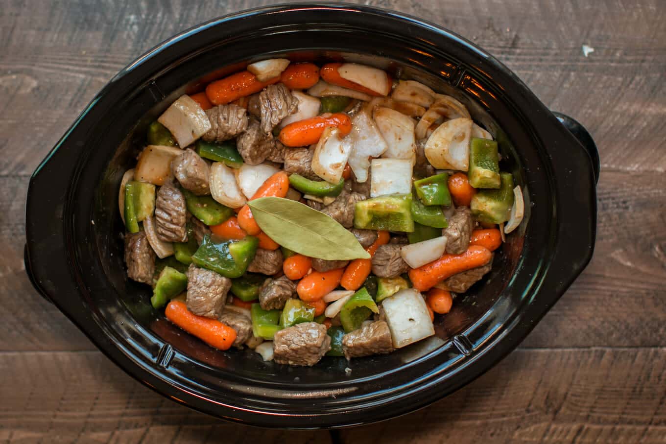 uncooked A1 beef stew in slow cooker with bay leaf on top.