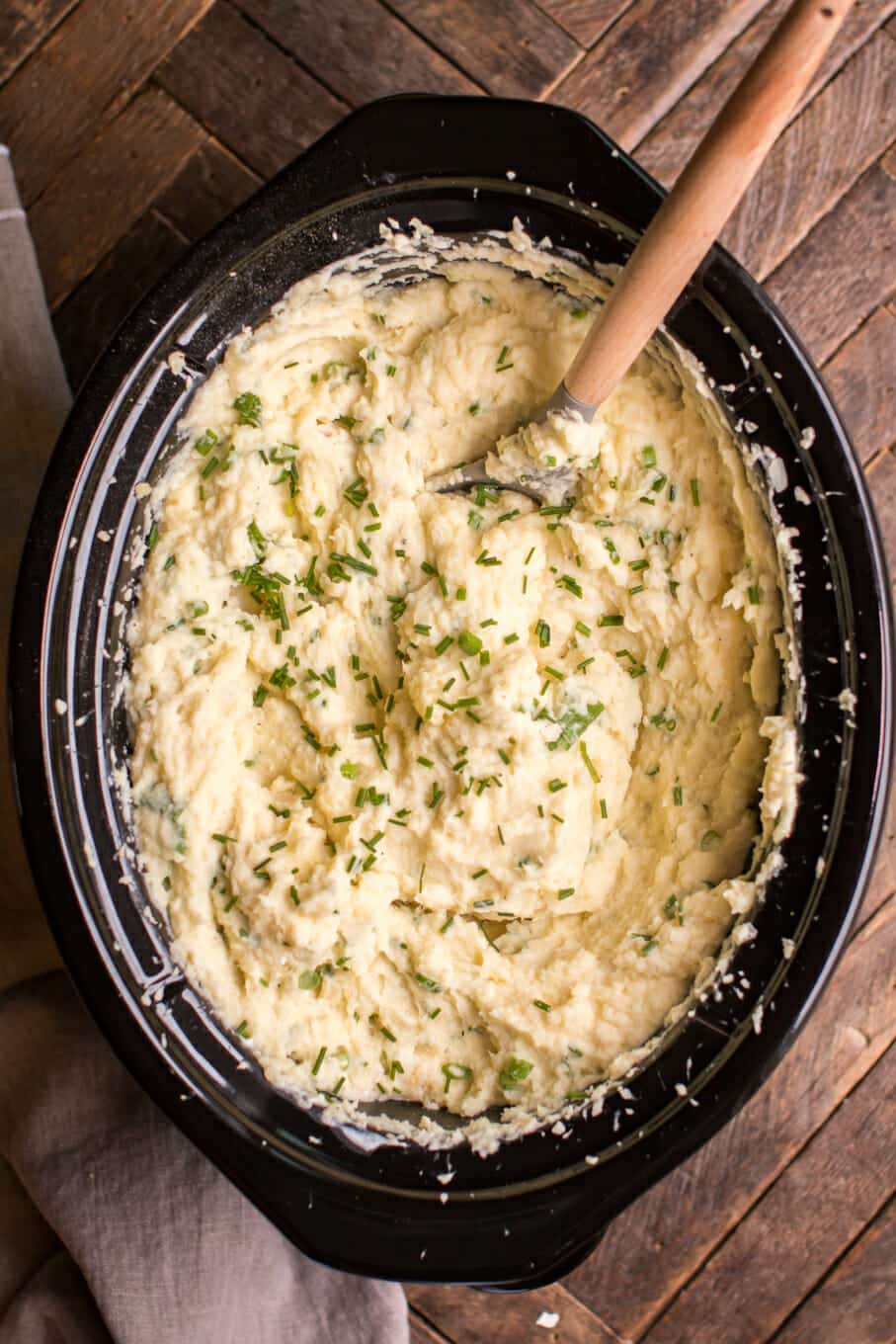 cooked sour cream and onion mashed potatoes with wooden spoon in it.