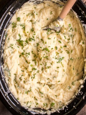mashed potatoes in slow cooker with chives on top.
