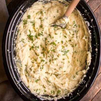 mashed potatoes in slow cooker with chives on top.