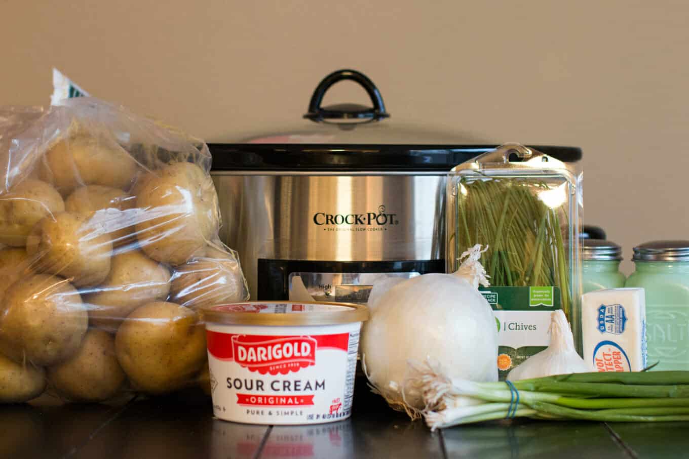 potatoes, sour cream, onion, chives and green onion in front of slow cooker.