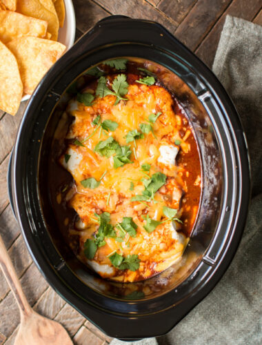 burritos smothered in red sauce with cheese and cilantro on top.