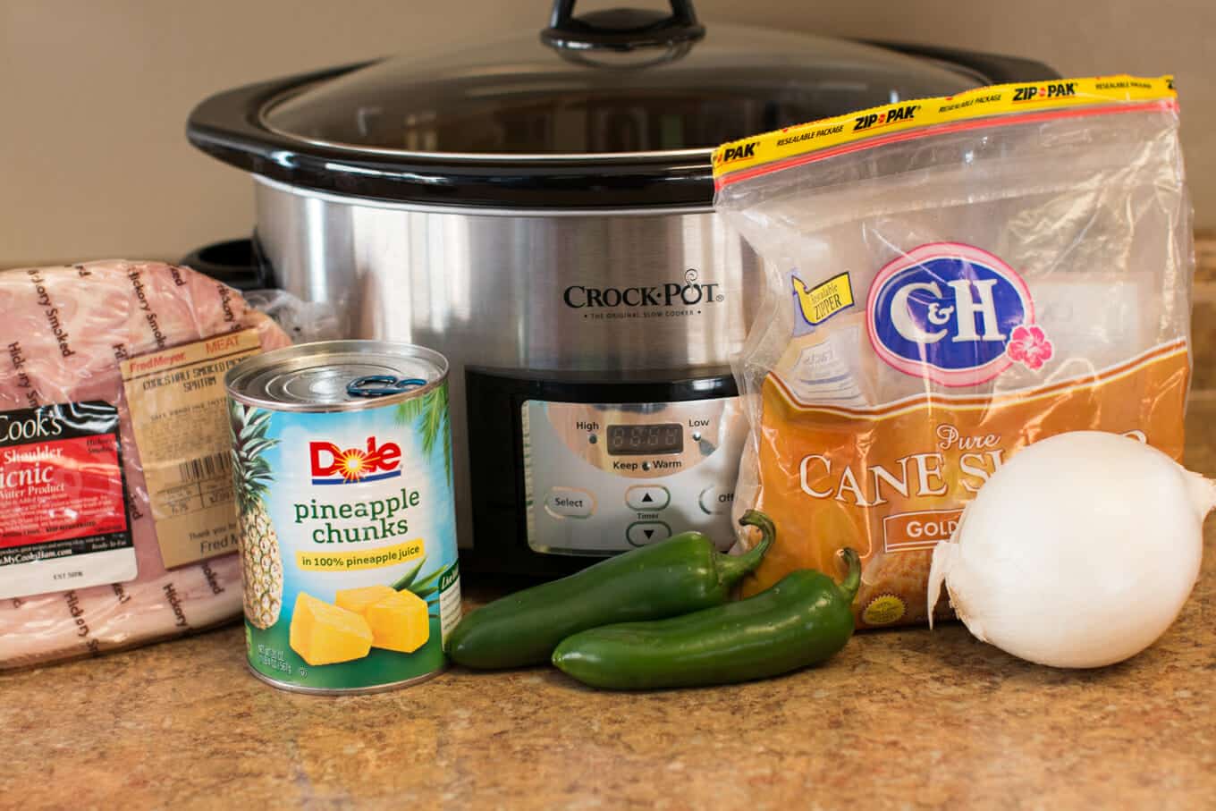 Ham, brown sugar, jalapenos, pineapple and onion in front of a slow cooker.