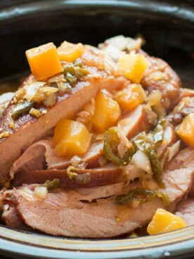 ham cut into slices with jalapenos and pineapple on top.