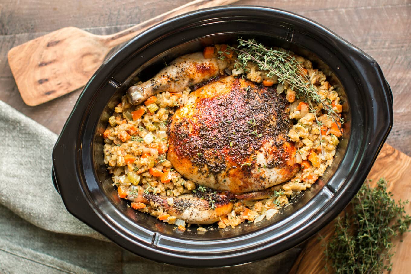 whole chicken in stuffing in the slow cooker with spatula on the side