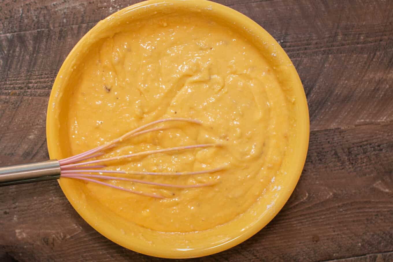 Yellow bowl with banana cake batter in it.