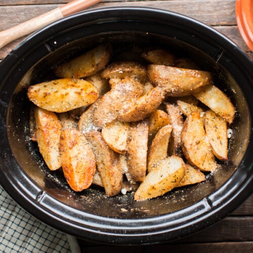 Potato wedges in slow cooker cooked with parmesan cheese and cajun seasonings.