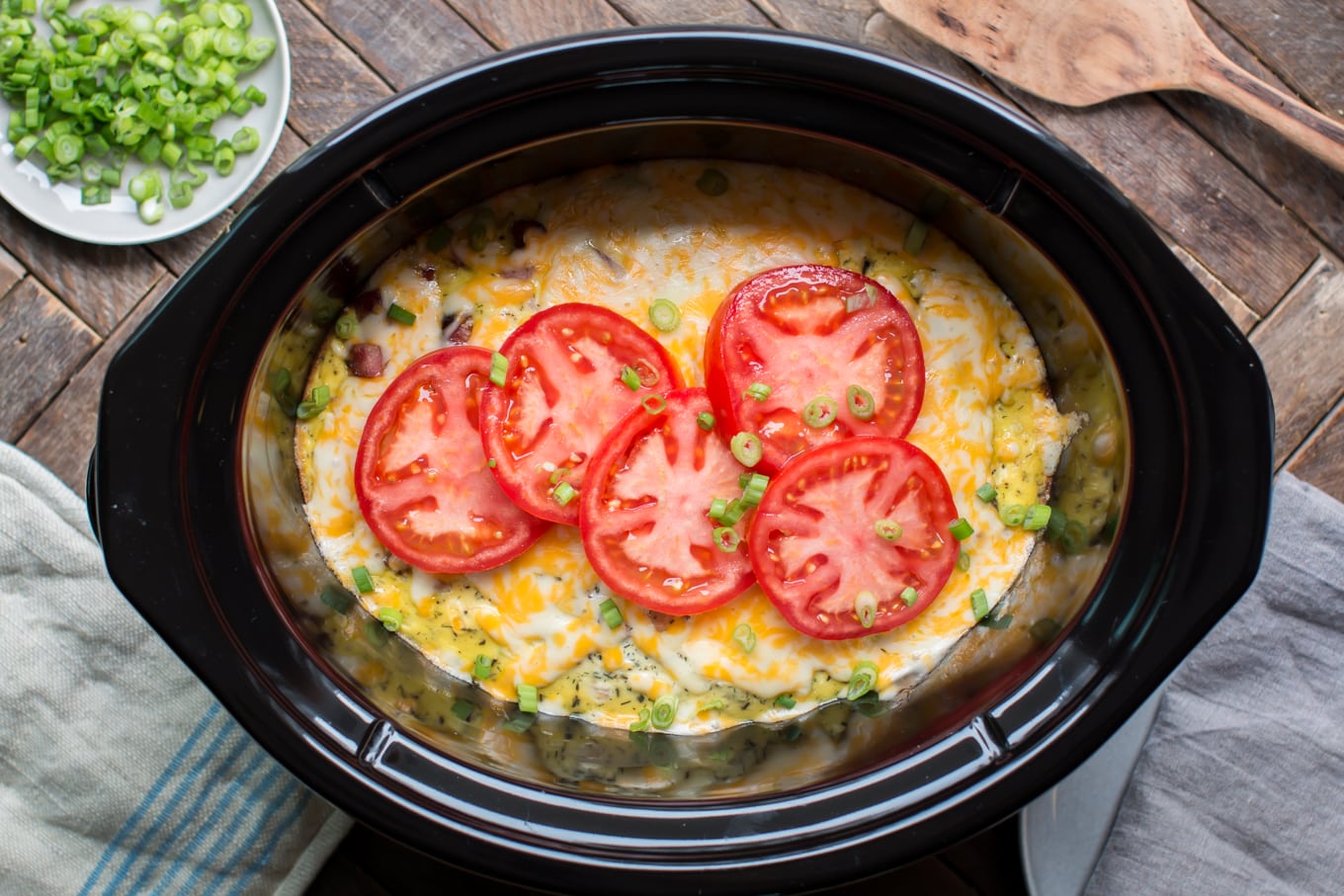 breakfast casserole in slow cooker with sliced tomatoes on top