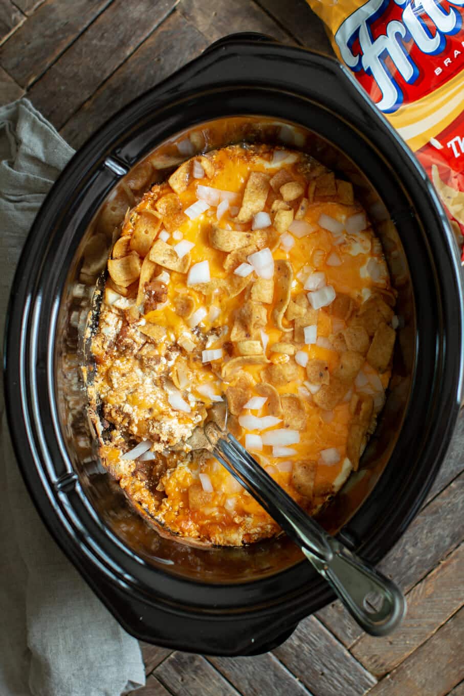 chili cheese casserole in a slow cooker with metal spoon in it.
