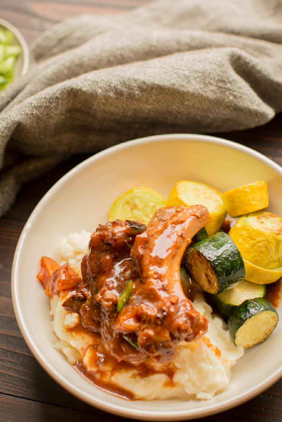 ribs on top of mashed poatoes with squash on the side.