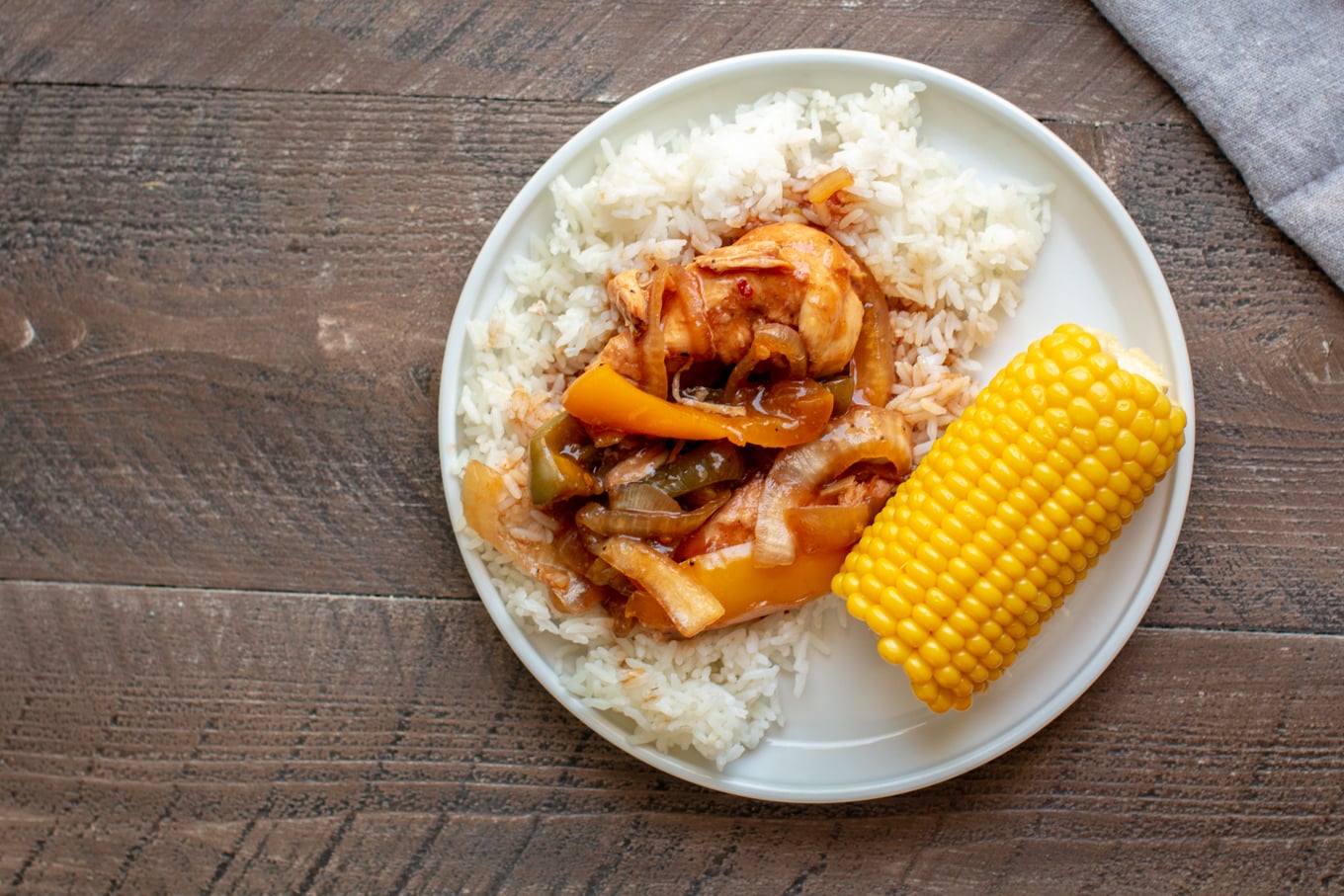 barbecue chicken on white rice on plate with corn