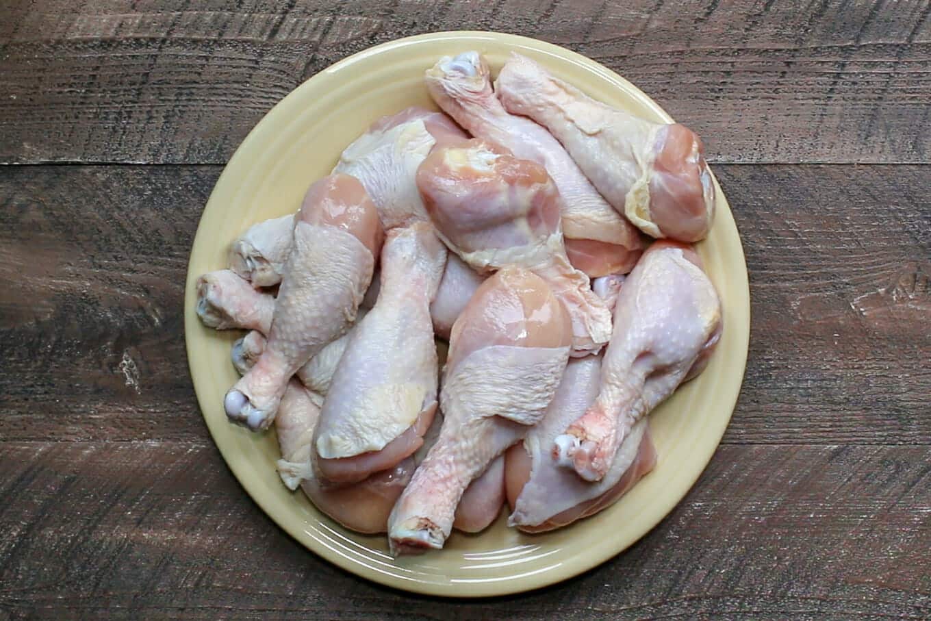 raw drumsticks on a yellow plate