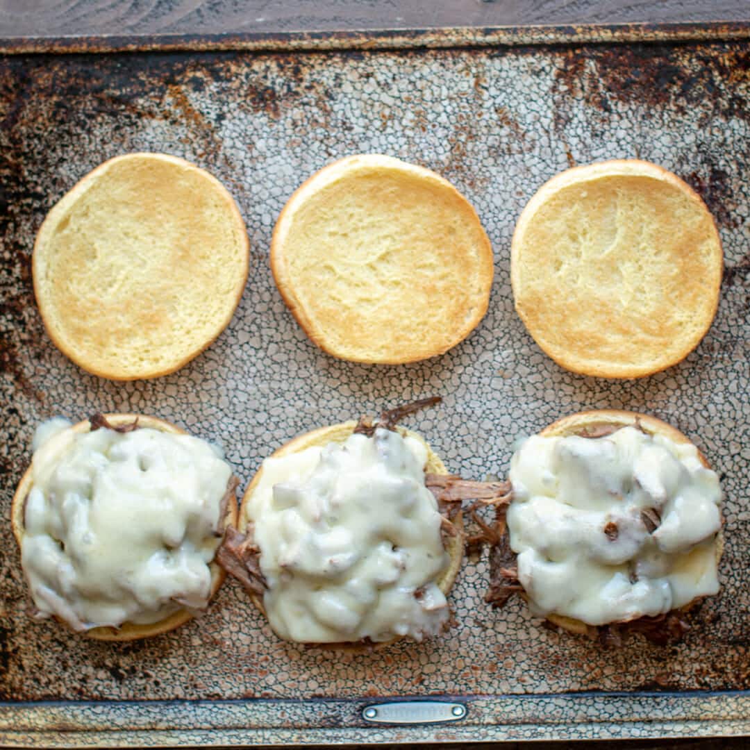 3 open face french dip sandwiches with swiss cheese on top.