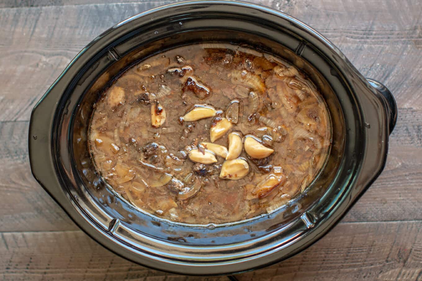 cooked roast in juices with onions and garlic in the slow cooker.