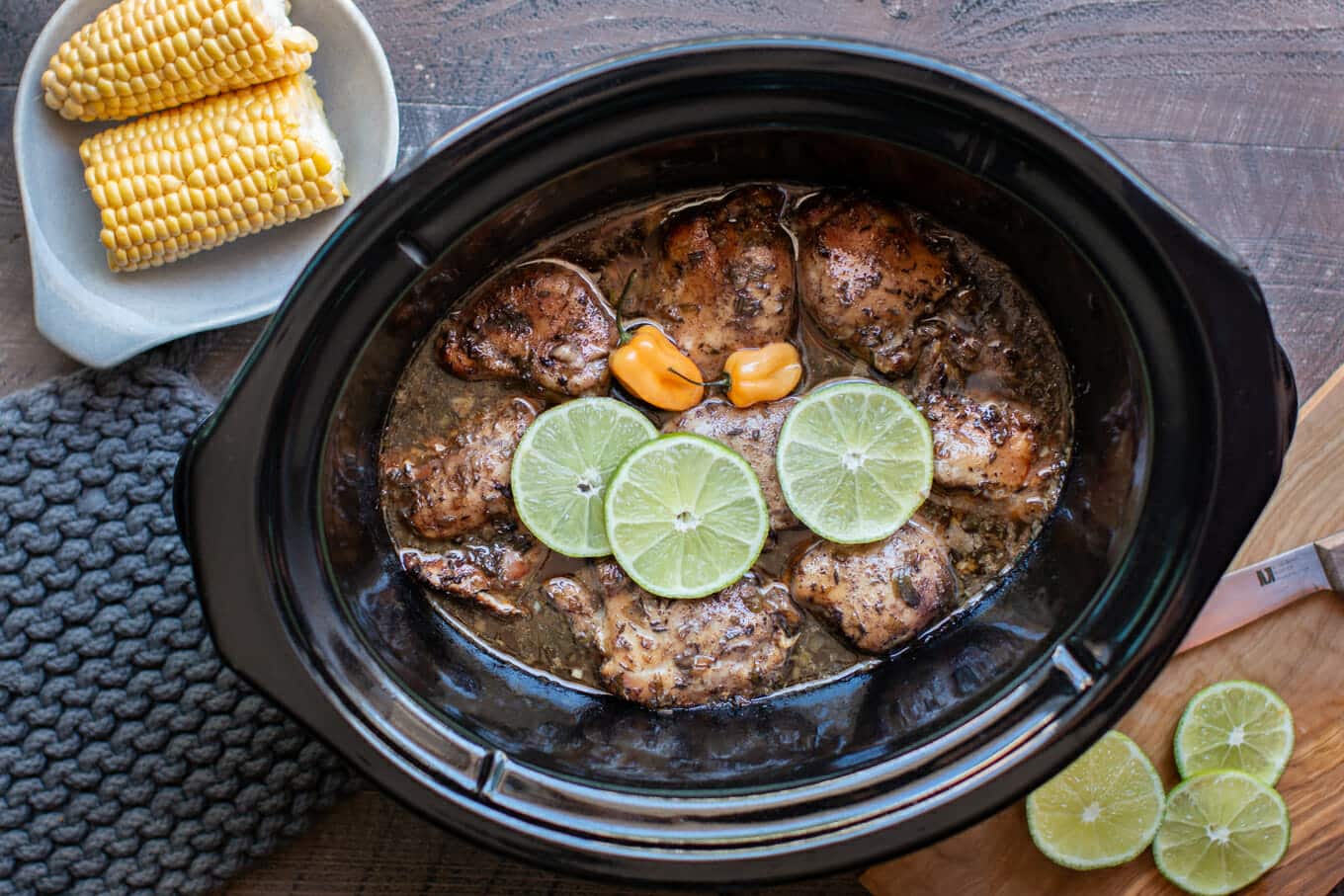 Jamaican jerk chicken in a slow cooker with limes and habanero on top.