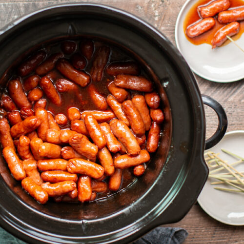 round slow cooker with little smokie wieners in it. Barbecue based sauce.