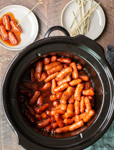 Barbecue little smokies in the slow cooker with a grey napkin on the side.