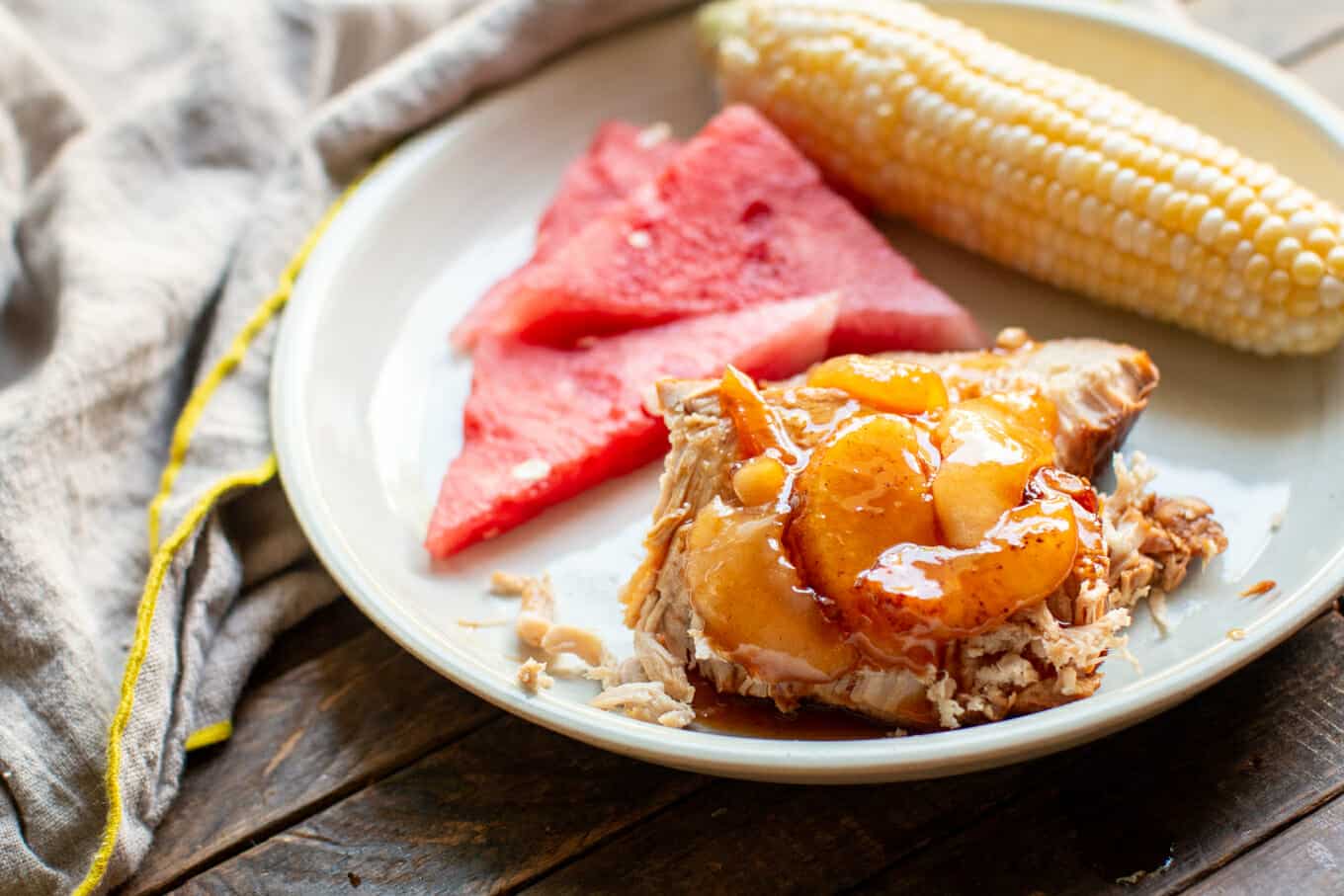 slice of pork loin with watermelon and corn on the cob.