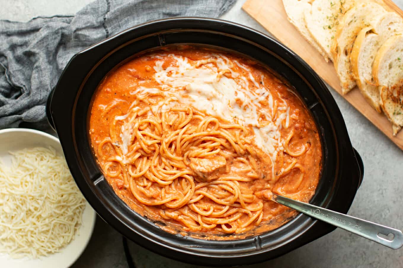 creamy chicken spaghetti with garlic bread and parmesan cheese on the side.