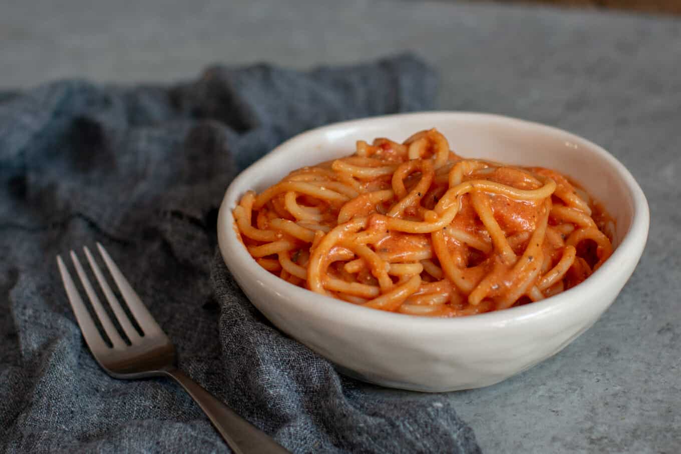 bowl of chicken spaghetti on grey napkin.