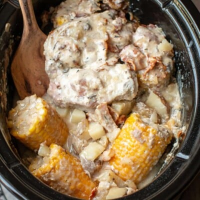 cooked pork chops, potatoes and corn cobs in a slow cooker.