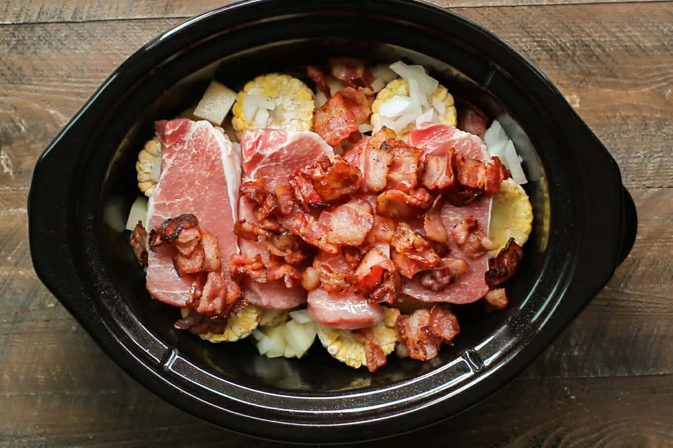 pork chops and bacon added on top of the corn and potatoes.