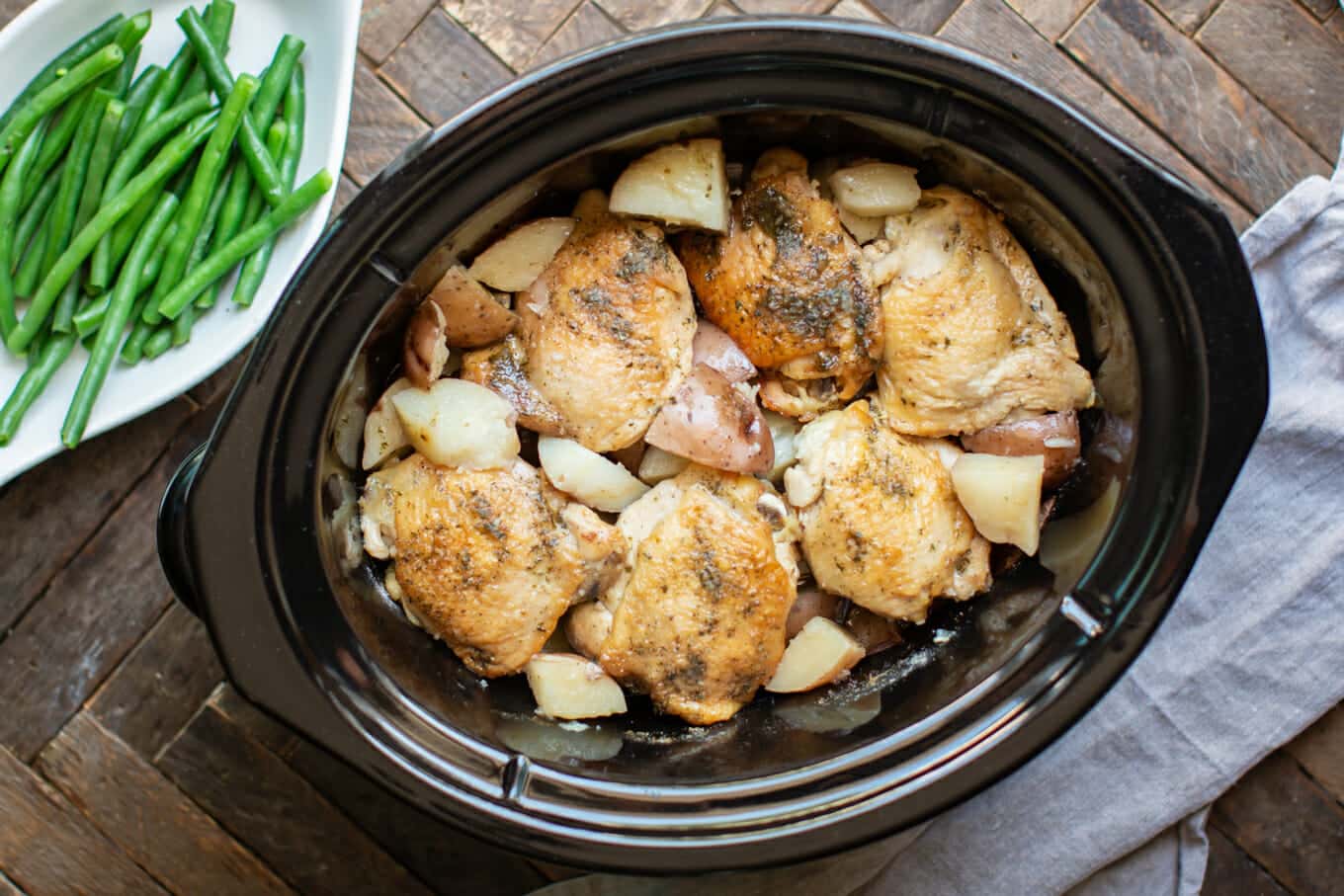 cooked chicken thighs with potatoes in a slow cooker