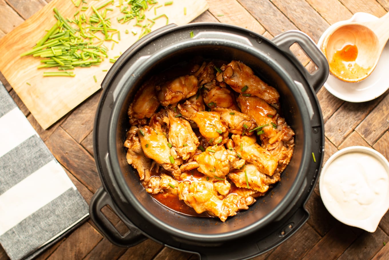 cooked wings in a pressure cooker with chives on top.