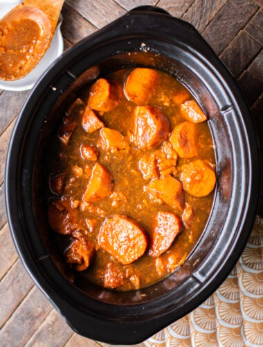 sliced cooked yams in a rich sauce in the slow cooker.