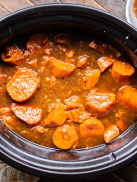 Cooked yams in rich colored sauce in the slow cooker