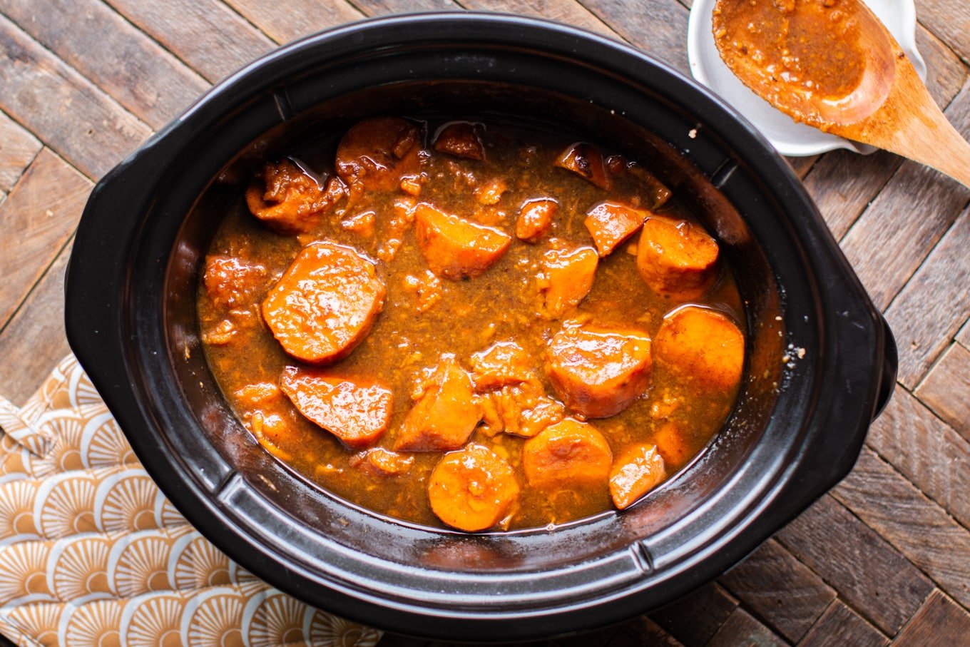 Cooked yams in rich colored sauce in the slow cooker.