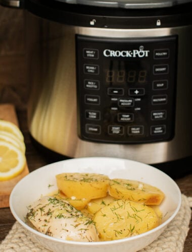 bowl of lemon chicken and potatoes in front of a pressure cooker.