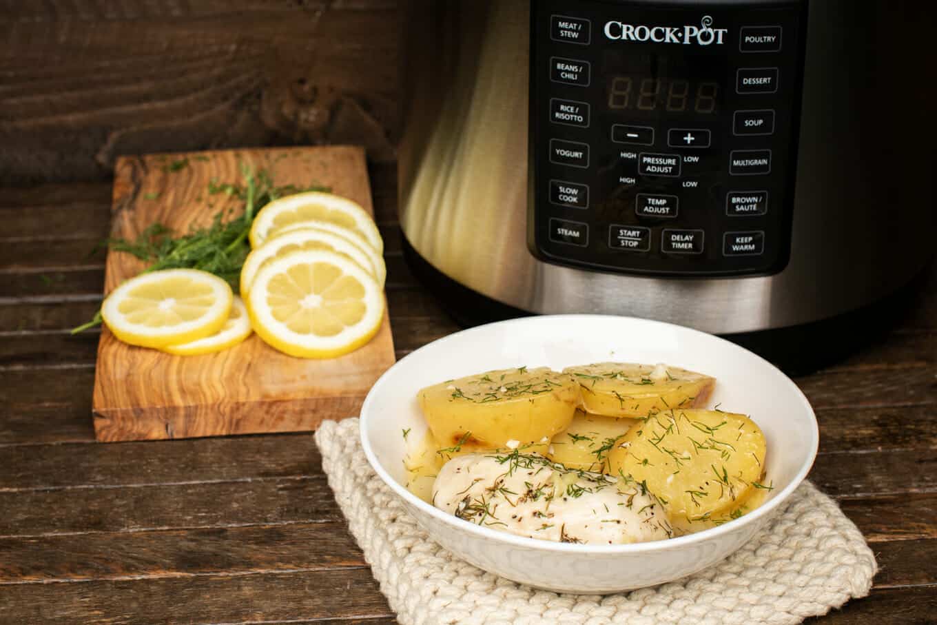 bowl on wooden table with chicken and potatoes.