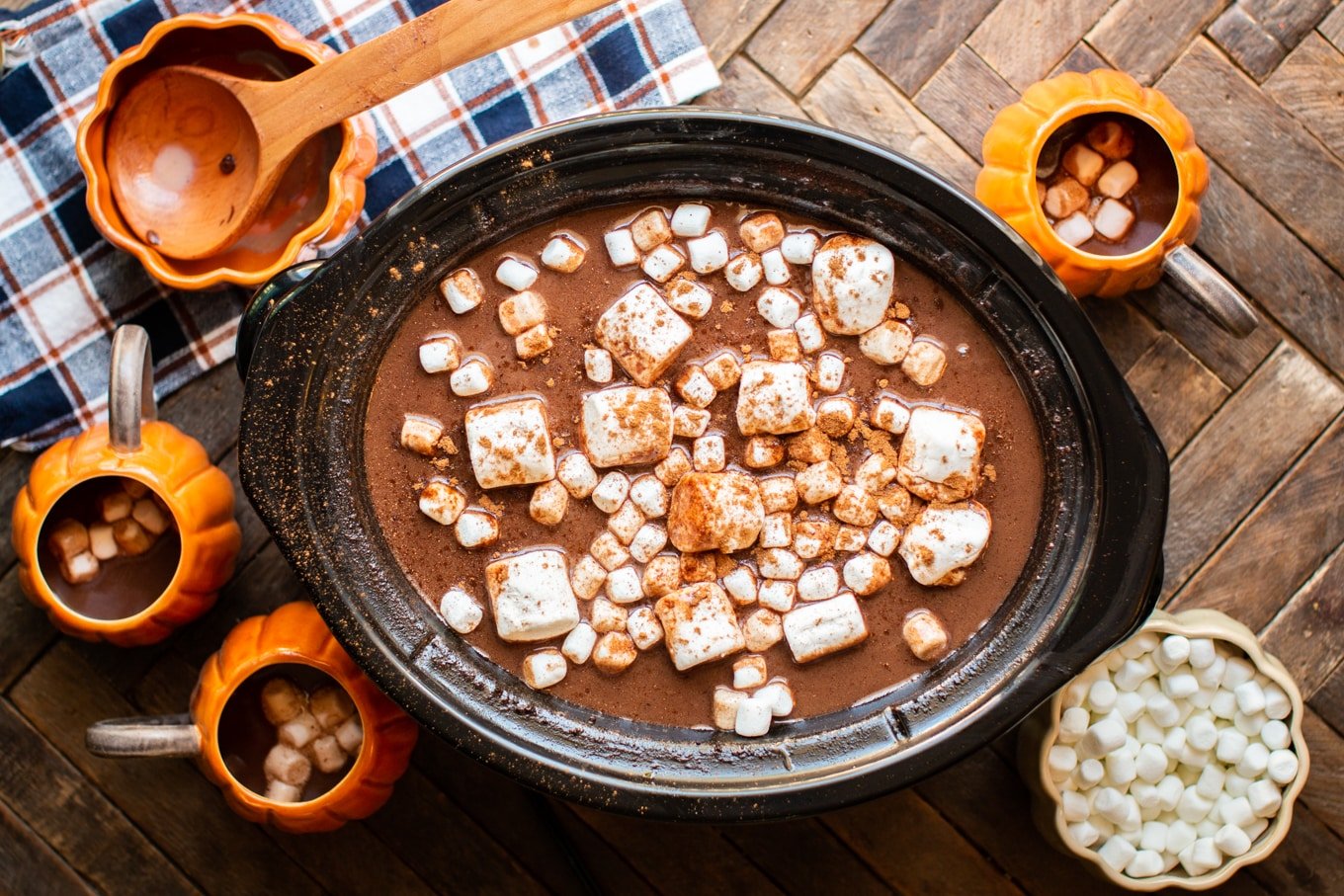 large and small marshmallows in pumpkin hot chocolate in a slow cooker.