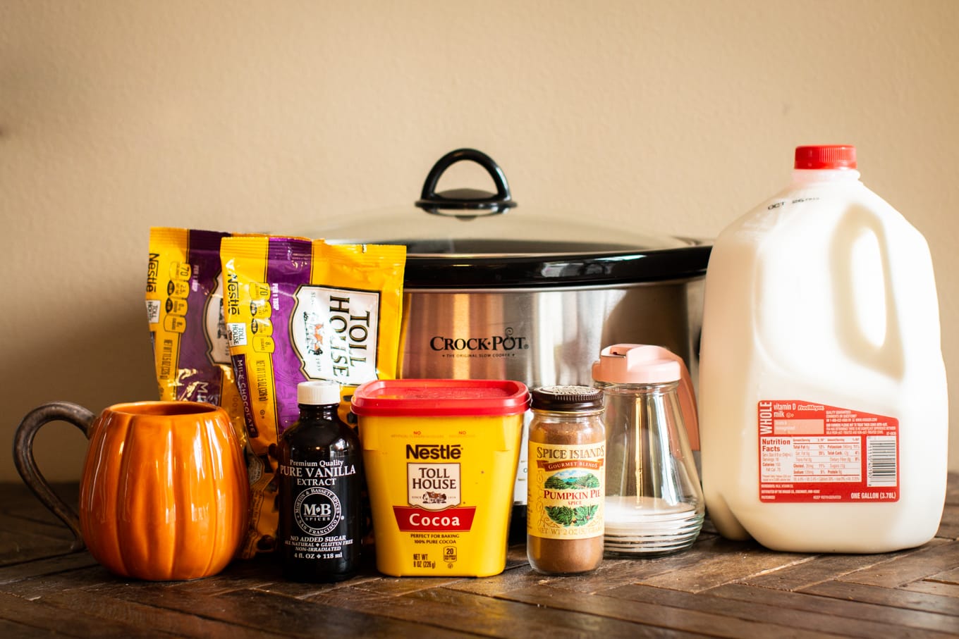 chocolate chips, milk, cocoa, vanilla, pumpkin spice mix, and sugar in front of a slow cooker