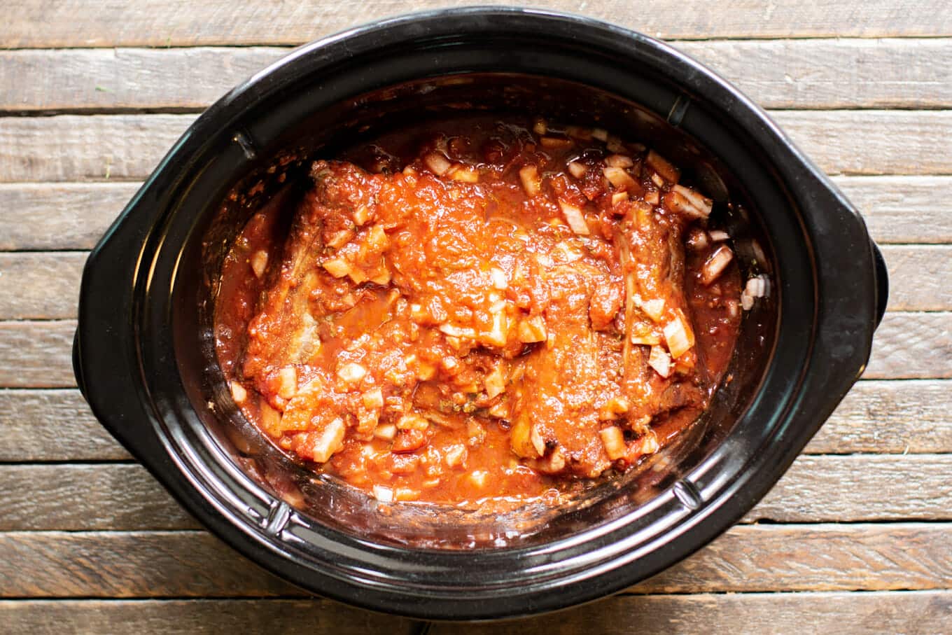 brown short ribs with marinara sauce on top, uncooked.