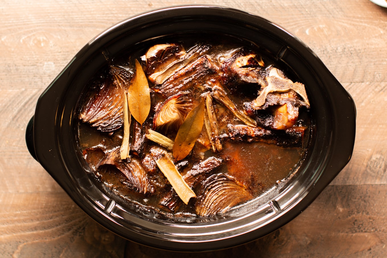 cooked beef bones and veggies in a slow cooker.