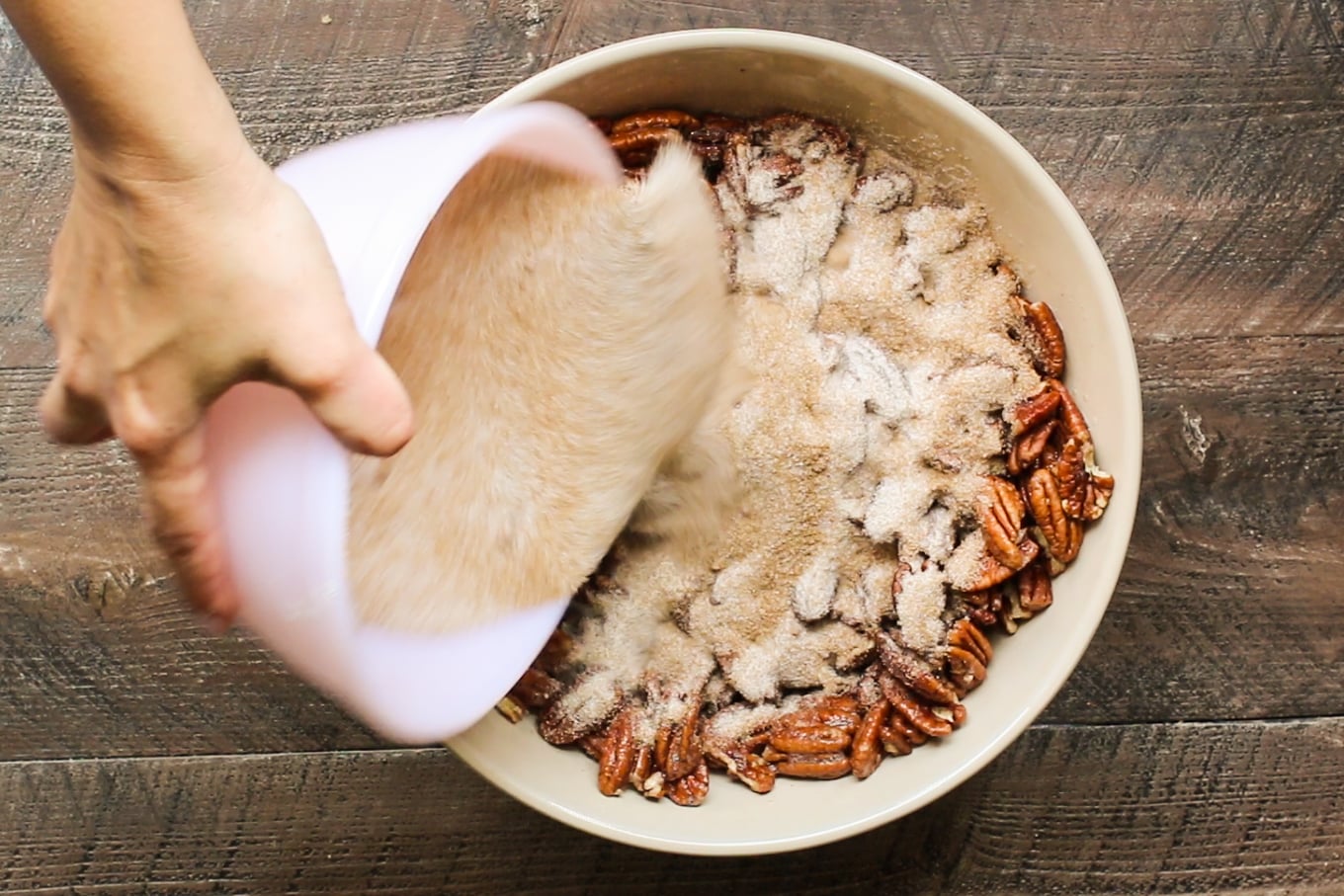 sugar mixture being poured over pecans.