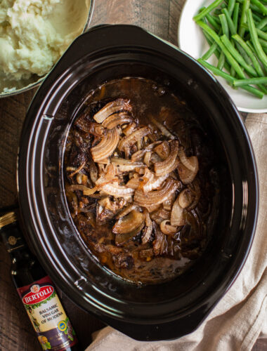 cooked beef roast in slow cooker with onions.