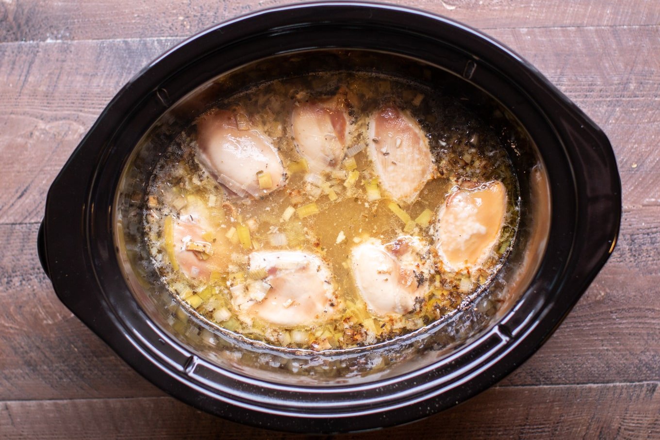 cooked chicken thighs in broth in a slow cooker.